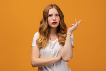 Studio shot of displeased girl with wavy redhead, gesturing with raised palm, frowning. Human emotions concept