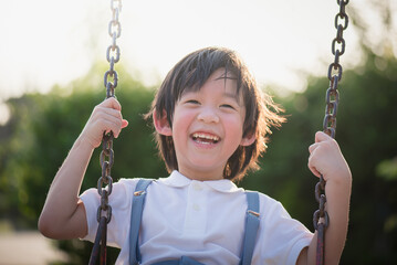 Cute Asian child having fun on swing in the park
