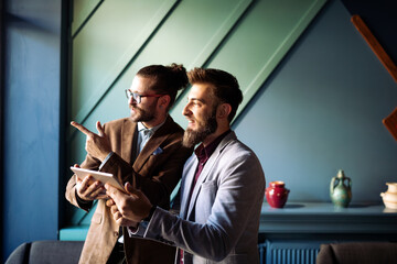 Portrait of happy businessmen using digital devices at meeting