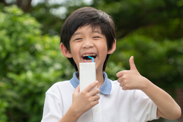 Cute Asian child  drinking a carton of milk from a box with a straw