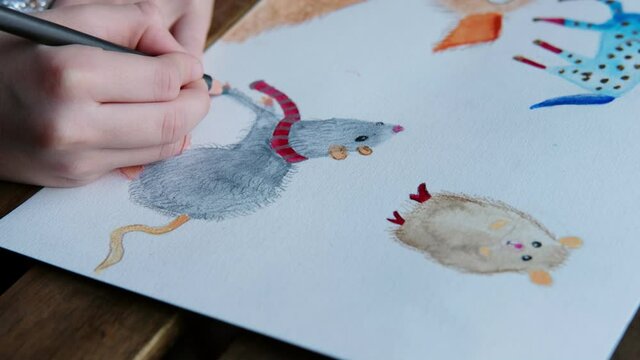 little girl draws a rat, a hamster, a horse on a sheet of paper with watercolors and pencils, children's creativity and drawing, concept