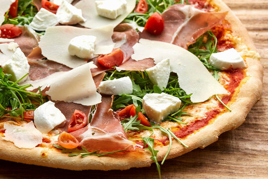 Pizza with cured ham, cheese and rocket
