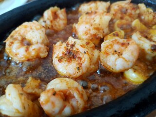 Fried shrimp with garlic on pan, preparing skillet with seafood, mediterranean cuisine concept.