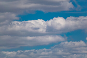 Obraz premium The blue sky is rich in color in clear weather with beautiful lush clouds. The beauty of nature in the fresh air, the layer of atmosphere visible to the eye from bottom to top