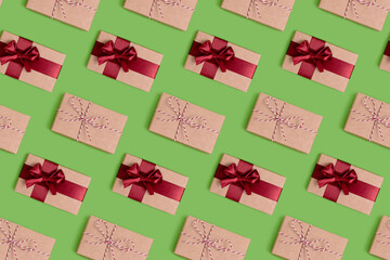 Repetitive pattern made of gift boxes tied with red ribbons on a green background. Art concept.