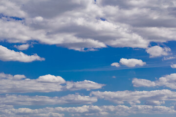 Obraz premium The blue sky is rich in color in clear weather with beautiful lush clouds. The beauty of nature in the fresh air, the layer of atmosphere visible to the eye from bottom to top