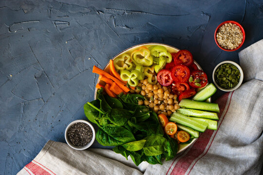 Buddha bowl with chickpea, baby spinach and other organic vegetables on concrete background