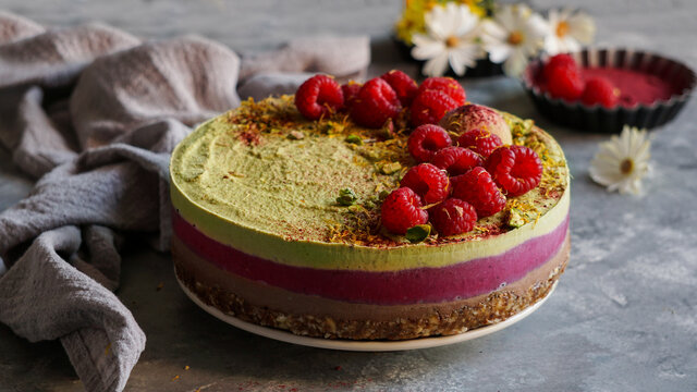 Vegan raw cashew cake with raspberries, coconut butter and coconut milk, and base made of almonds, dates