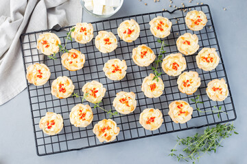 Mini quiche muffins with feta cheese, fried onion, thyme and red bell pepper, on cooling rack, horizontal, top view
