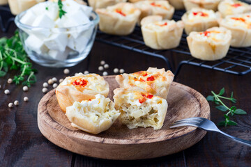 Feta cheese and fried onion mini quiche muffins, on wooden plate and cooling rack, horizontal
