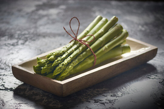 A bundle of green asparagus in a wooden dish