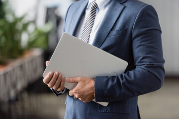 Cropped of executive in formal wear holding laptop on blurred background