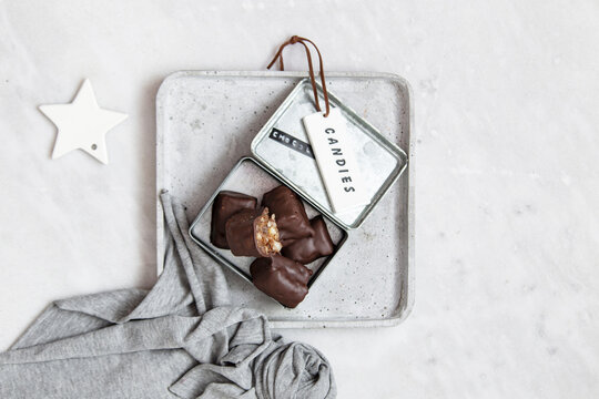 Chocolate candy with nuts and dates in gift box on white marble background