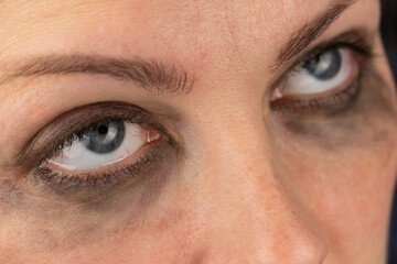 Obraz premium Close-up of female gray eyes looking up with smudged mascara.