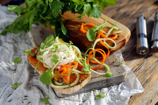 sandu&iacute;che aberto com ovo escalfado, salm&atilde;o, vegetais e ervas.
