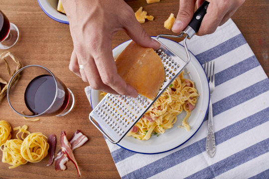 Parmesan being grated over pasta carbonara