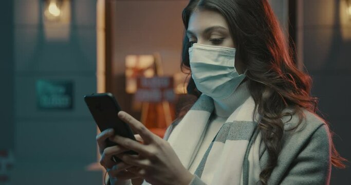 Woman wearing a surgical mask and connecting with her phone