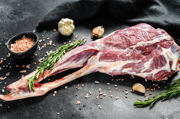 Raw goat leg with salt and garlic. Farm meat. Black background. Top view
