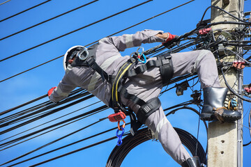 Electricians are carefully repairing damaged electrical systems on Electric pole with high-security...