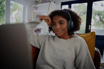 Happy woman watching online video with headphones at home relaxing on couch