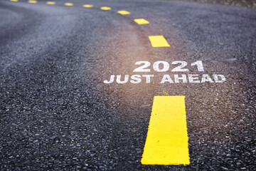 2021 just ahead written on asphalt road with marking lines for giving directions. Beginning business challenge concept and new year success idea