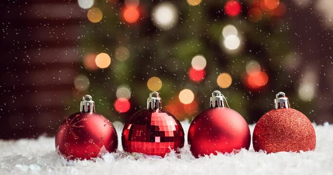 Animation of four red christmas baubles decoration with snow falling