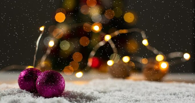 Animation of christmas decorations, baubles and lights with snow falling