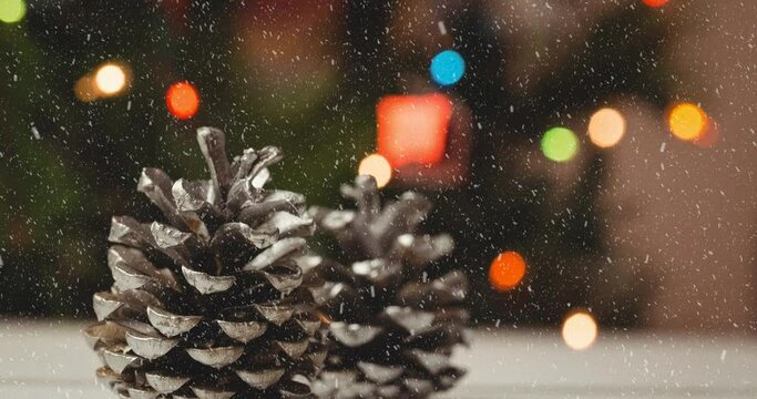 Animation of christmas pine cones, lights and decorations with snow falling
