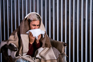 A guy with a cold is sitting at home.