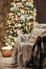 armchair with warm blanket and decorated Christmas tree. Concept of Merry Christmas and New Year