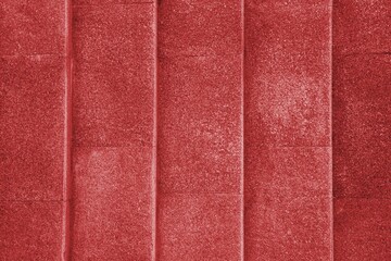 Fototapeta premium Large red textured concrete wall with vertical lines and a pattern of repeating dots.