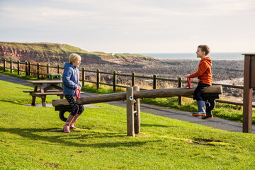 A young brother and sister playing on a seesaw in a park at Crail, Fife, Scotland. This park is on...