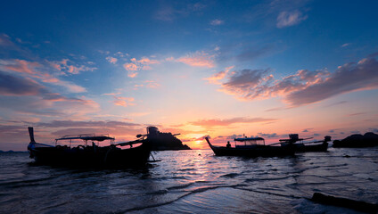Fototapeta na wymiar Silhouette of wooden boat in sea with sunset and blue sky at Lepe Island in Thailand