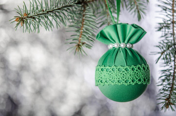 One green Christmas ball on a fluffy spruce branch.