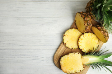 Slices of fresh pineapple on white wooden table, flat lay. Space for text