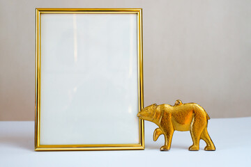 Empty gold picture frame on white background. Mock up frame with gold bear figurine. Winter empty frame. Autumn background. Winter composition. Cozy house. Copy space. Christmas decoration