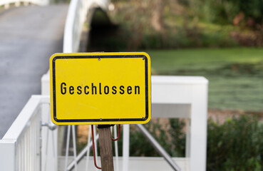 Yellow sign on a bridge with the German word for closed