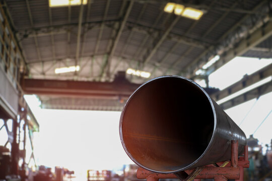 Large diameter pipes are stacked in an industrial factory shop