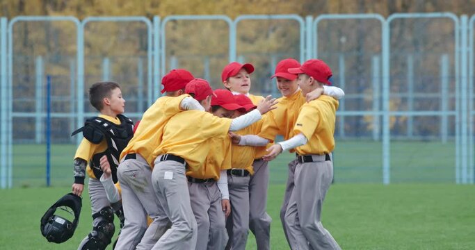 Baseball at school, a team of boys baseball players in yellow uniforms get hugs and rejoices in victory, successful game, positive emotions, 4k Slow Motion.
