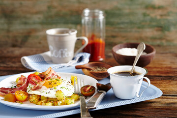 Fried potatoes, bacon, fried egg and tomatoes and breakfast with coffee