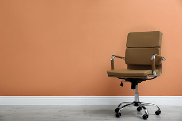 Modern office chair near orange coral wall indoors. Space for text