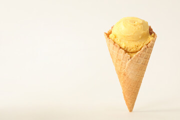 Delicious yellow ice cream in waffle cone on white background. Space for text