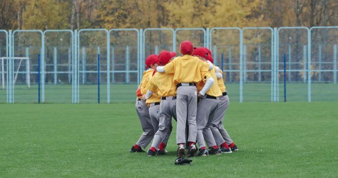 Baseball at school, a team of boys baseball players in yellow uniforms get hugs and rejoices in victory, successful game, positive emotions, 4k Slow Motion.