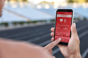 Man using fitness app on smartphone at stadium, closeup