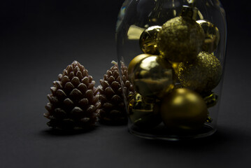 an inverted glass with beautiful golden balls stands on a black background. next to it are two...