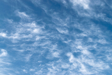 White feathery fluffy clouds on a blue sky, background and texture