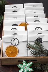 Paper bags, cookie and festive decor on wooden table, closeup. Christmas advent calendar