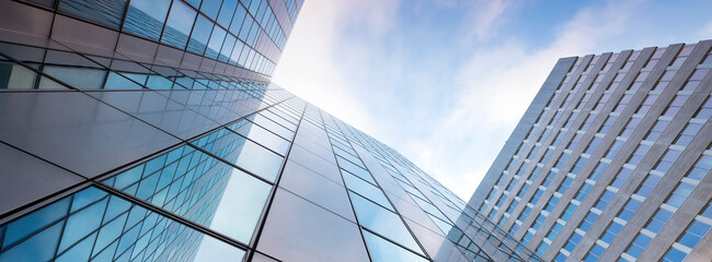 glass facades of modern office buildings and reflection of blue sky - 395495773