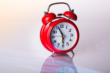 Red alarm clock close up on white glass table