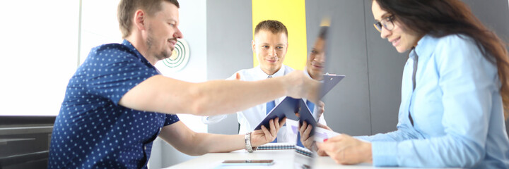 Obraz premium Two men and woman are sitting at table at meeting with documents and laptop in office. Buying and selling business concept.